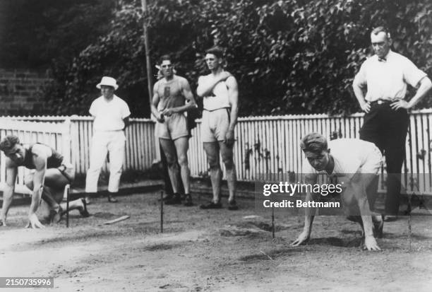 Coach Lawson Robertson of the American Olympic Team is shown at the right directing the training of the American athletes. At the right, on the mark,...