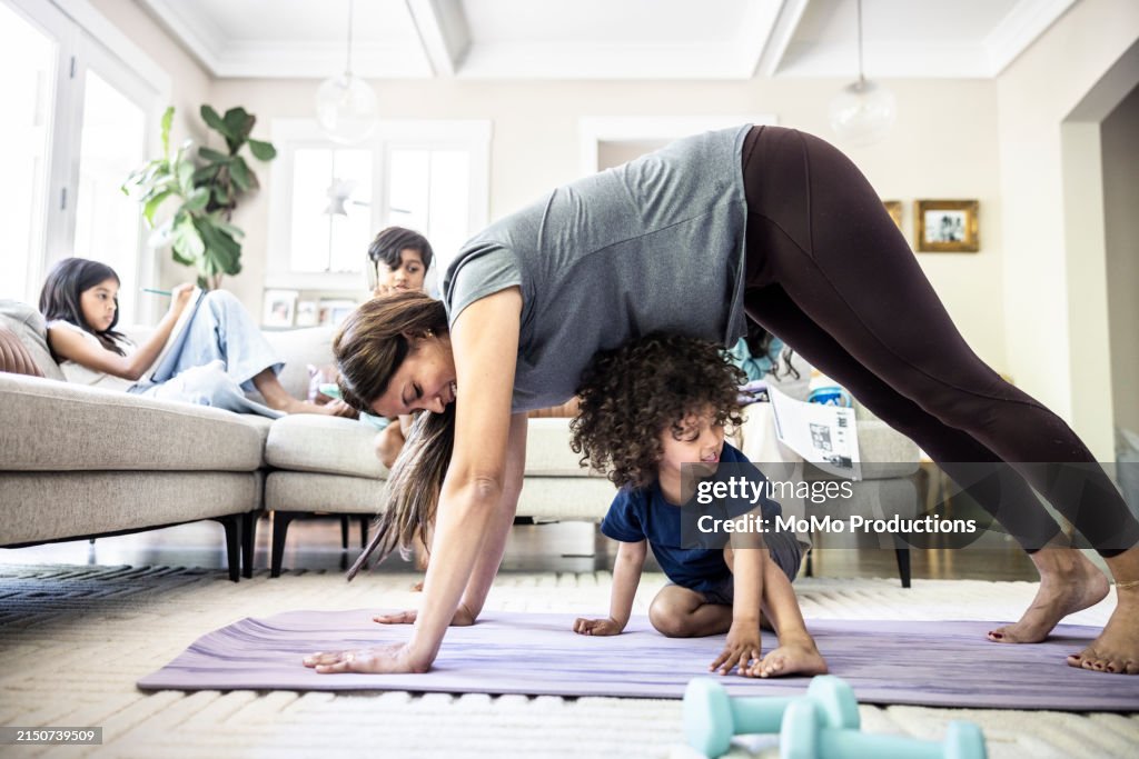 Mother exercising at home while distracted by toddler boy