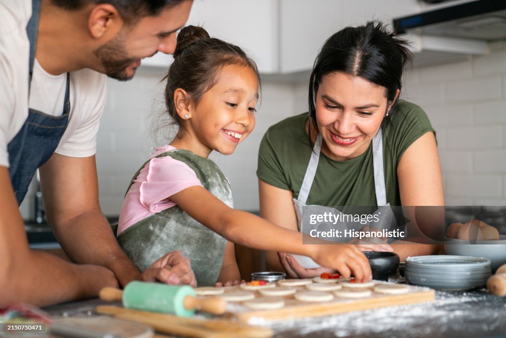 Happy girl baking at home with her loving parents
