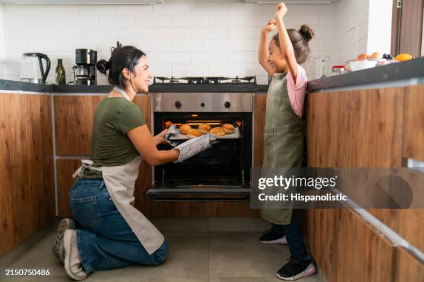 madre e hija horneando en casa y sacando pasteles del horno - horno cocina fotografías e imágenes de stock