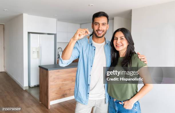 loving couple holding the keys of their new house - sleutel beveiligingsapparatuur stockfoto's en -beelden