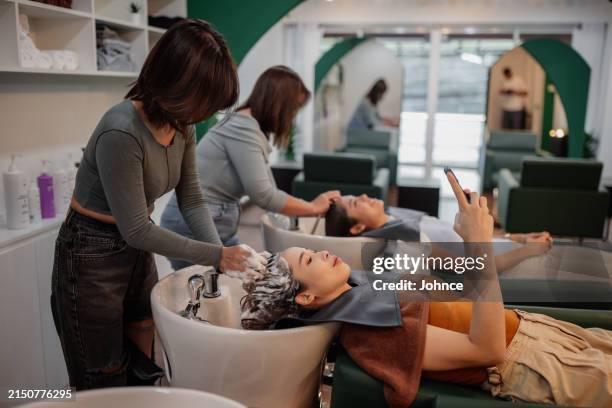 smiling woman using phone at hair salon - hair salon images free stock pictures, royalty-free photos & images