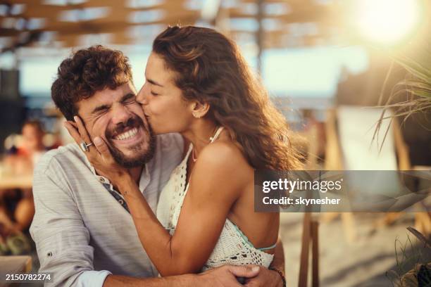glücklicher mann, der einen kuss von seiner freundin am sommertag genießt. - wange stock-fotos und bilder