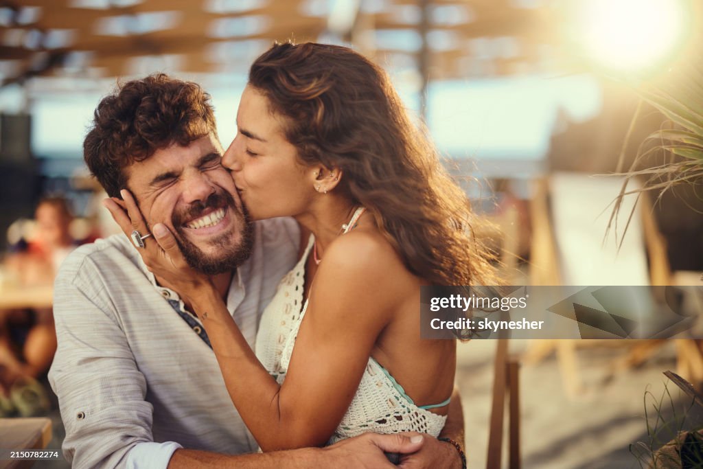 Happy man enjoying in a kiss by his girlfriend in summer day.