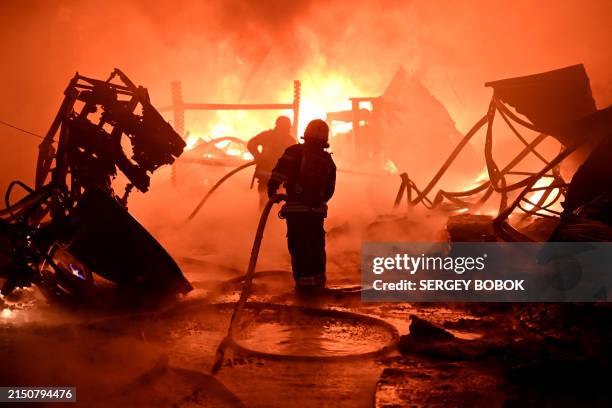 Ukrainian firefighters work to extinguish a fire at the site of a drone attack on industrial facilities in Kharkiv on May 4 amid the Russian invasion...