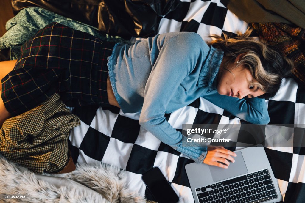Woman lying on bed with laptop