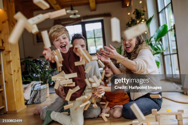portrait of nuclear family having fun, playing with wooden blocks, throwing them and laughing. perfect family moment, weekend activities. - block removal game stock pictures, royalty-free photos & images