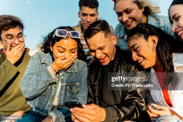 friends talking and looking at photos on mobile phone - gossip stock pictures, royalty-free photos & images