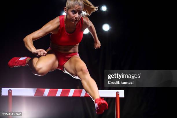 hurdling female athlete in the middle of the jump - track and field event stock pictures, royalty-free photos & images