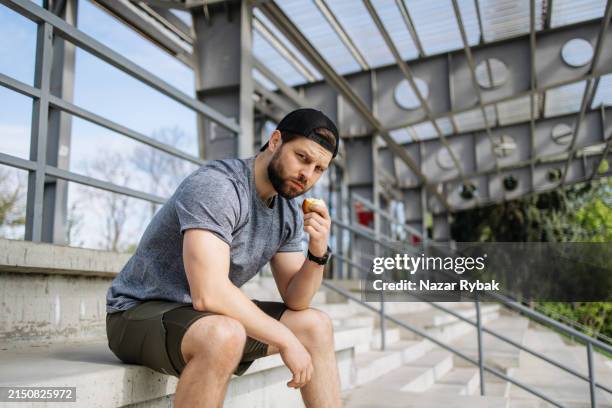 post-training refuel: sportsman enjoys apple after stadium workout - post workout snack stock pictures, royalty-free photos & images
