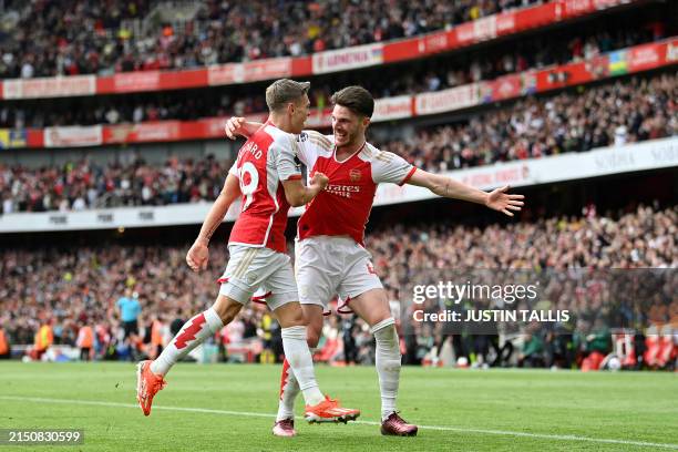 Arsenal's Belgian midfielder Leandro Trossard celebrates with Arsenal's English midfielder Declan Rice after scoring the team's second goal during...