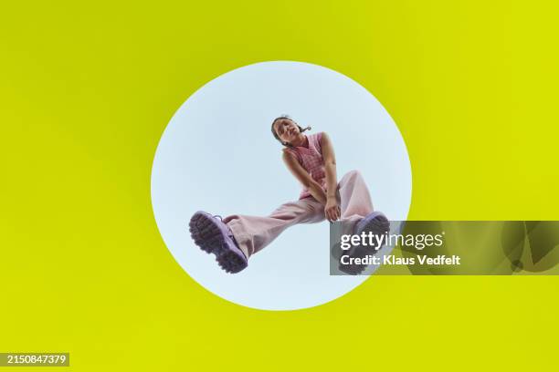 young woman levitating mid-air in white circle - grüne schuhe stock-fotos und bilder