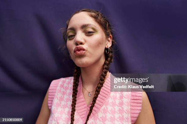 young woman pulling braided hair puckering lips - hacer pucheros fotografías e imágenes de stock