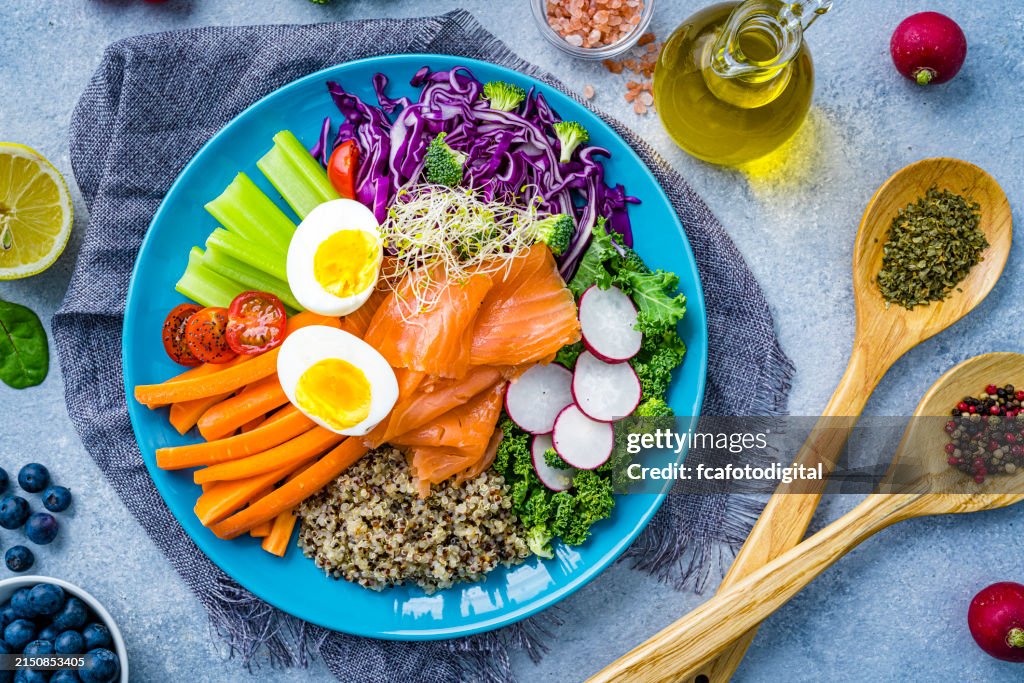 Overhead view of a fresh salmon, quinoa, boiled eggs and vegetables salad plate. Healthy eating and dieting concept