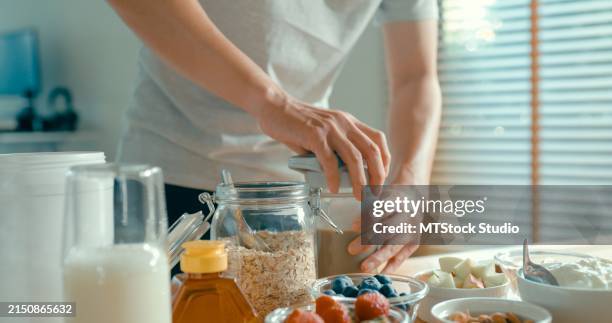 primer plano de un joven asiático preparando un batido de proteínas en una casa moderna. dieta y rutina matutina de alimentación saludable. - aminoácido fotografías e imágenes de stock
