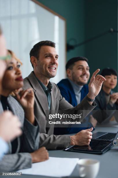 smiling business man in the audience raising his hands to ask a question on a business seminar - vragen en antwoorden stockfoto's en -beelden