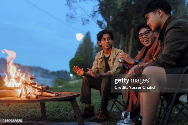 teenage boys warming up around campfire - ocio fotografías e imágenes de stock