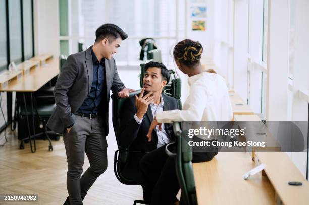 in the workplace, three multiracial coworkers are talking about the project. - filipino people working stock pictures, royalty-free photos & images