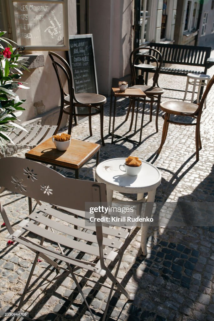 Quaint street café setup in Lesser Town, Prague, on a sunny morning.