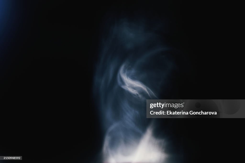 Swirling vortex of smoke in a dynamic play of light and shadow on black background
