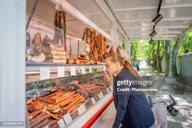 mujer comprando en carnicería móvil - charcutería italiana fotografías e imágenes de stock
