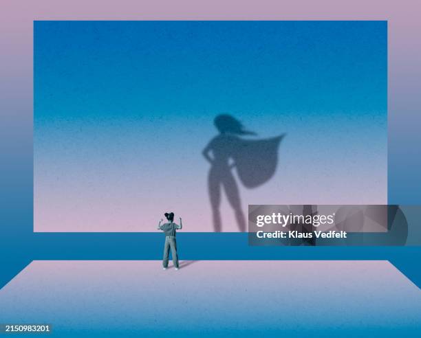 girl flexing muscles in front of superwoman - superhero stock pictures, royalty-free photos & images
