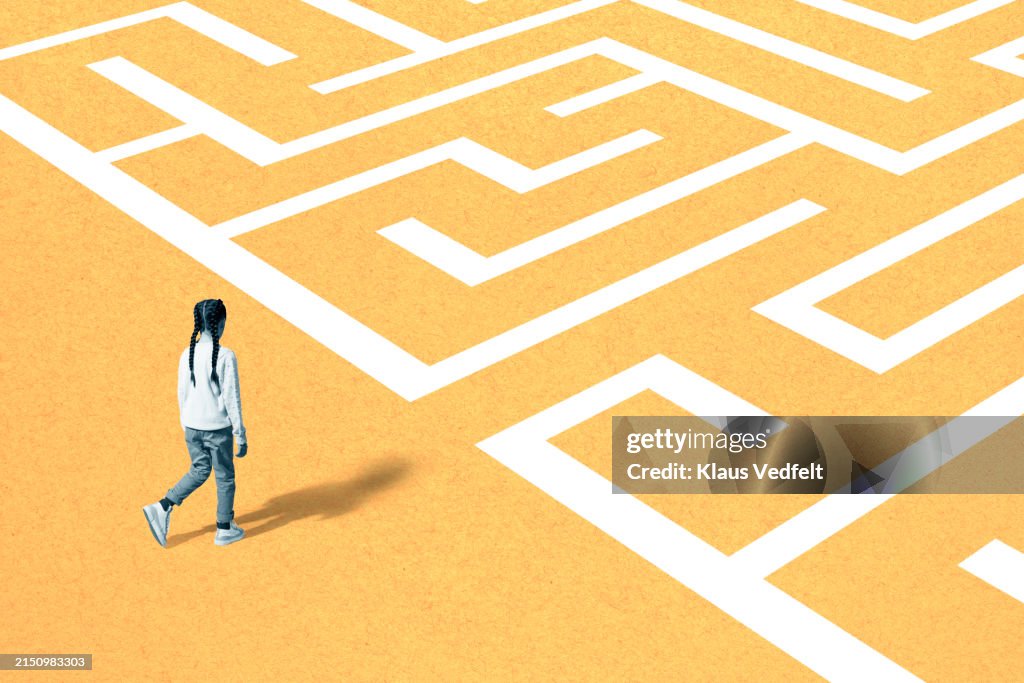 Girl walking towards maze on yellow surface