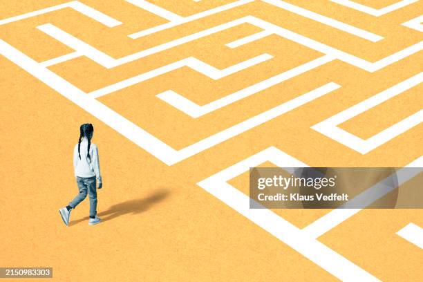 girl walking towards maze on yellow surface - labirinto imagens e fotografias de stock