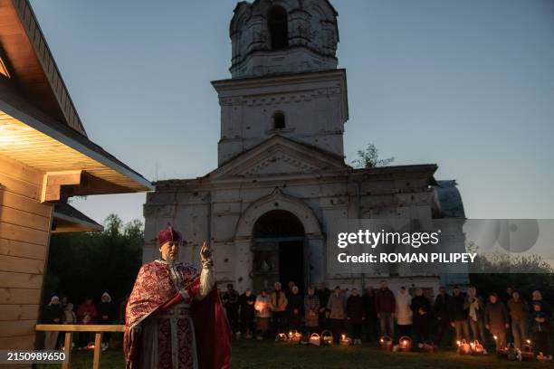 Ukrainian priest Serhii speaks to Orthodox devotees carrying baskets of traditional Easter delights on Orthodox Easter outside the Church of the...