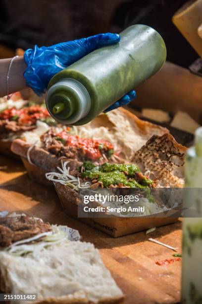 adding salsa verde over honey truffle and pork ciabatta - borough market stock pictures, royalty-free photos & images