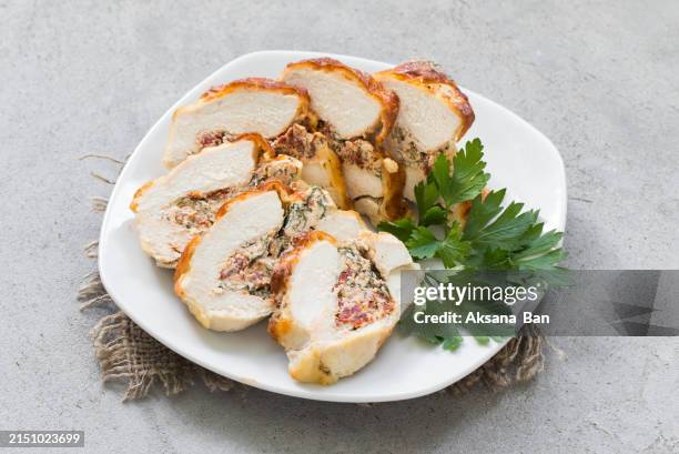 baked chicken fillet stuffed with spinach, cottage cheese, dried tomatoes. on a plate with parsley. on a linen napkin/ close-up - stuffed stock pictures, royalty-free photos & images