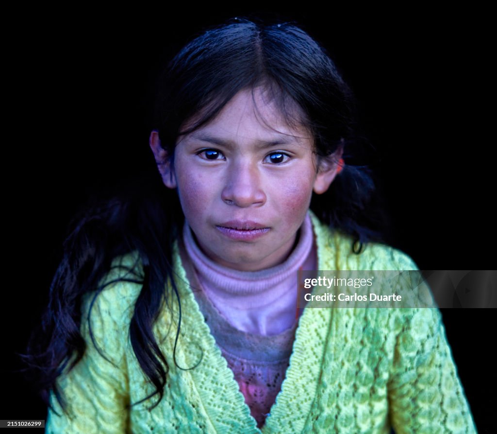 Portrait of a Quechua girl of the Quero ethnic group with black studio background