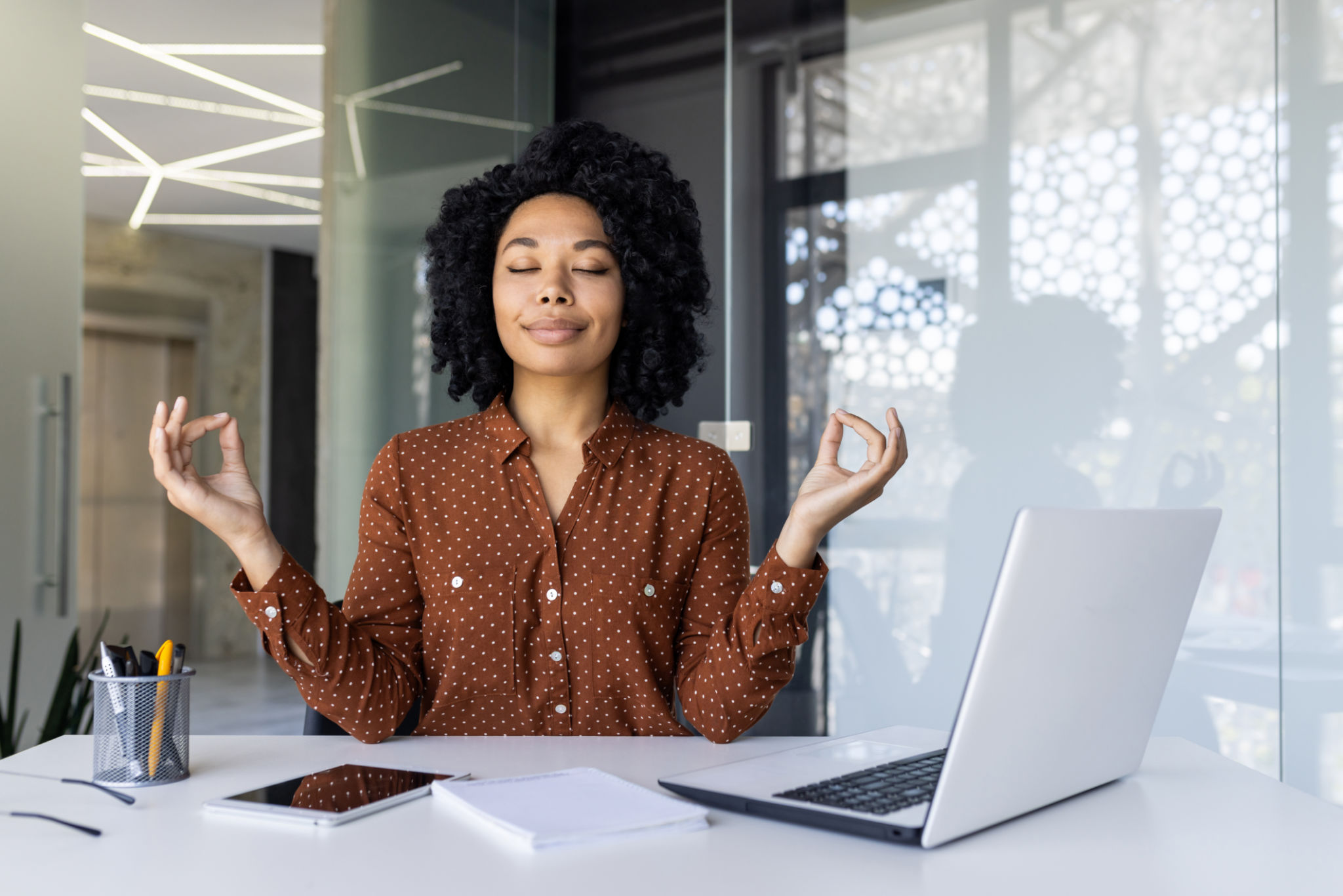 Businesswoman practicing meditation at her office desk Businesswoman practicing meditation at her office desk