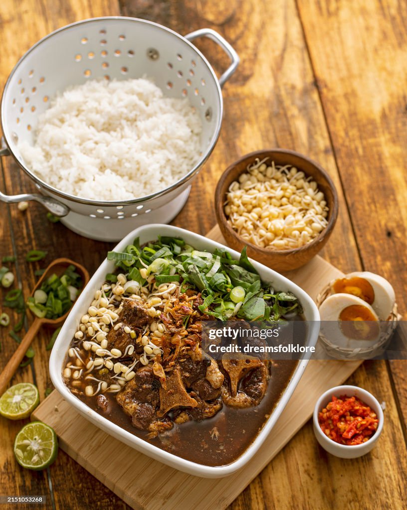 Rawon or black beef soup , a soup with dark broth and savory taste, served with salted egg and rice