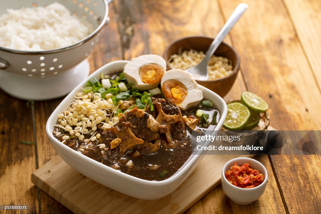 Rawon or black beef soup , a soup with dark broth and savory taste, served with salted egg and rice