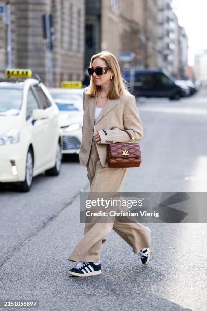Sonia Lyson is seen wearing beige Herskind suit, brown Louis Vuitton bag, YSL sunglasses, white shirt on May 01, 2024 in Berlin, Germany.