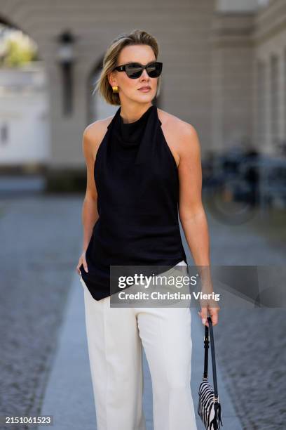 Tina Haase is seen wearing Massimo Dutti black halterneck top, Zara cream suit pants, Mango Zebra print bag, Chanel sunglasses on May 01, 2024 in...
