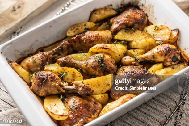 baked chicken legs with sliced potatoes and herbs. barbecue chicken drumsticks. potatoes with chicken baked in the oven. delicious dish for lunch or dinner. - baking tray stock pictures, royalty-free photos & images
