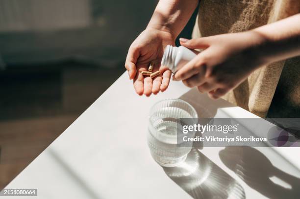 hand with pills and water glass - comprimido imagens e fotografias de stock