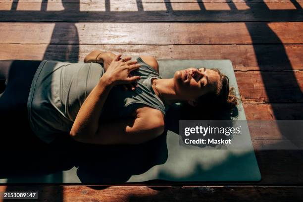 high angle view of woman lying down with eyes closed on yoga mat at wellness resort - meditação imagens e fotografias de stock