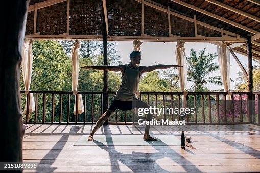 Mature man practicing Warrior 2 pose while exercising at wellness resort Mature man practicing Warrior 2 pose while exercising at wellness resort