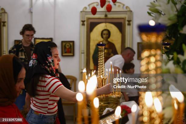 Worshippers light candles celebrating Easter ceremony on the Holy Sunday, at the Orthodox Church of the Dormition of the Virgin Mary in Krakow,...