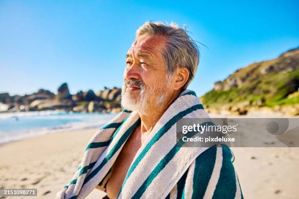 joyful senior asian man with towel on beach, laughing under the sun. outdoor beach lifestyle. summer and wellness concept. - striped towel stock pictures, royalty-free photos & images