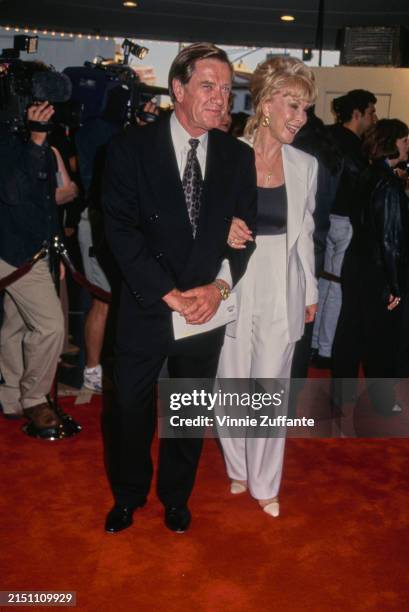 American architect Jon Eicholtz, wearing a black suit over a white shirt and a silver-and-black tie, and his wife, American actress Barbara Eden, who...