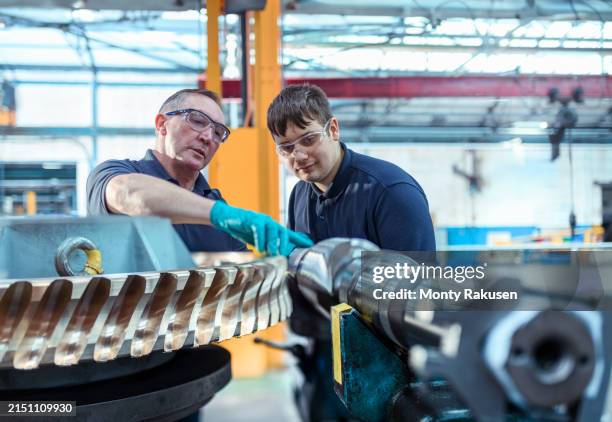 engineer mentoring apprentice with worm gears in engineering factory - engineering stock pictures, royalty-free photos & images