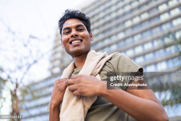 smiling young man in casual attire outdoors - dichterbij komen stockfoto's en -beelden