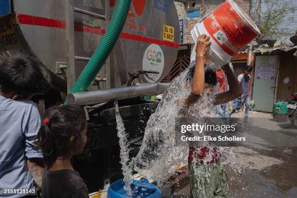 Boy cools himself with potable water from the New Delhi Municipal Council water tanker on May 02, 2024 in New Delhi, India. A few residents purchased...