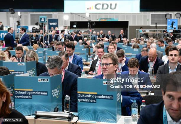 Members of Germany's Christian Democratic Union sit behind voting boxes bearing the inscription "Winning the future together" during a voting test on...