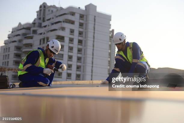 veduta aerea di due ingegneri solari che lavorano sul tetto di un edificio in una grande città - tetto foto e immagini stock