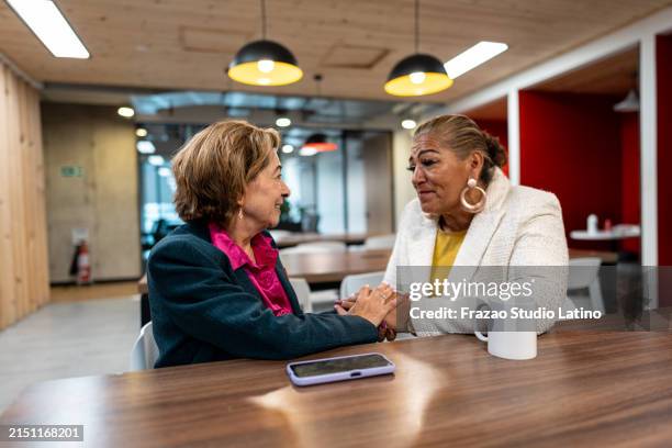senior businesswoman consoling coworker in the office - empathie stockfoto's en -beelden